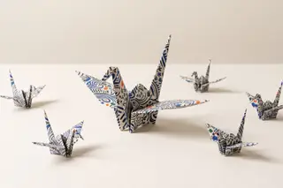 One large patterned origami crane surrounded by six smaller cranes folded from the same paper