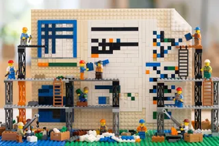 Toy brick builders on scaffolding assembling a large resume page out of white and colored bricks